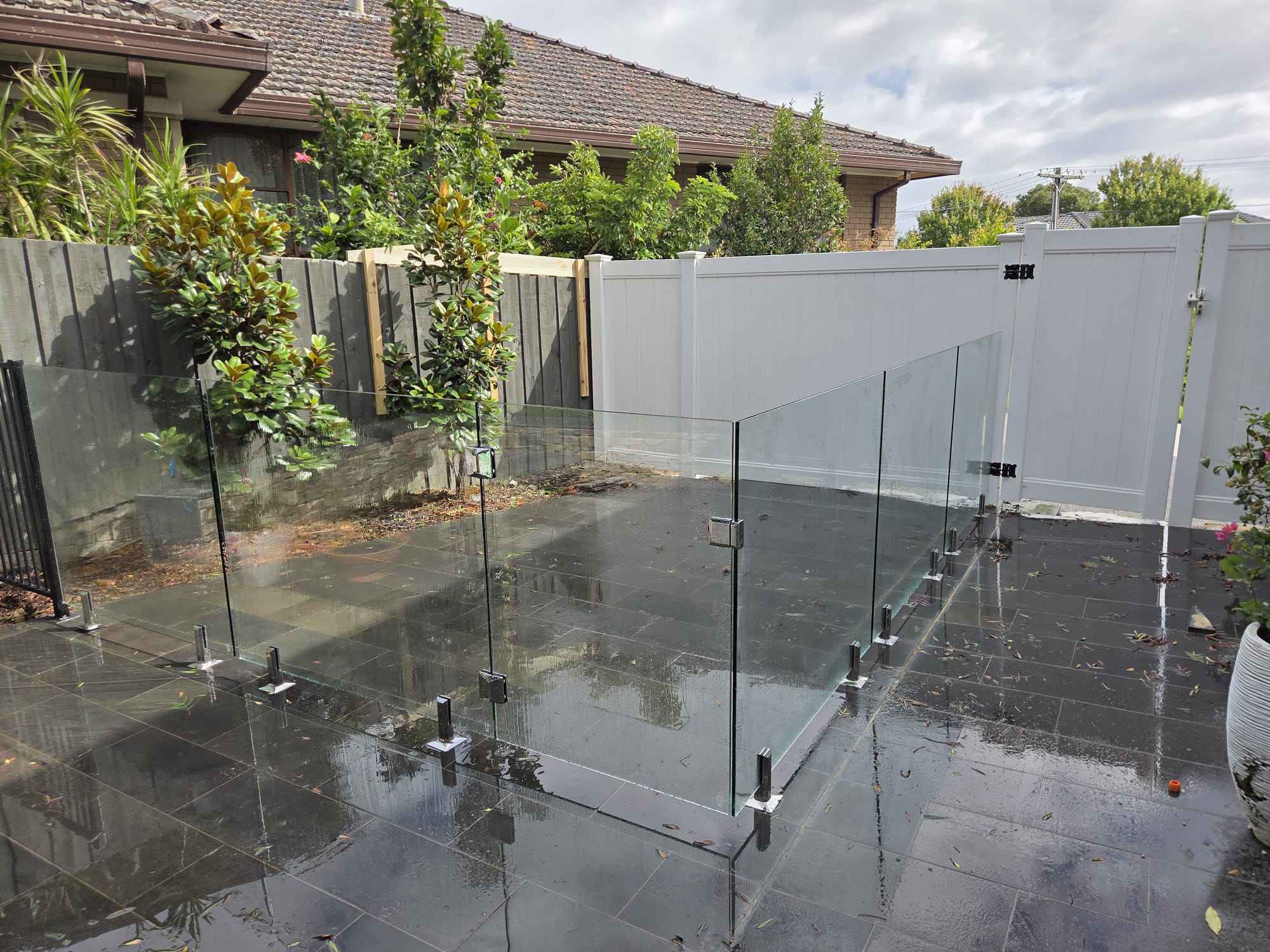 Frameless glass pool fence enclosing a paved courtyard